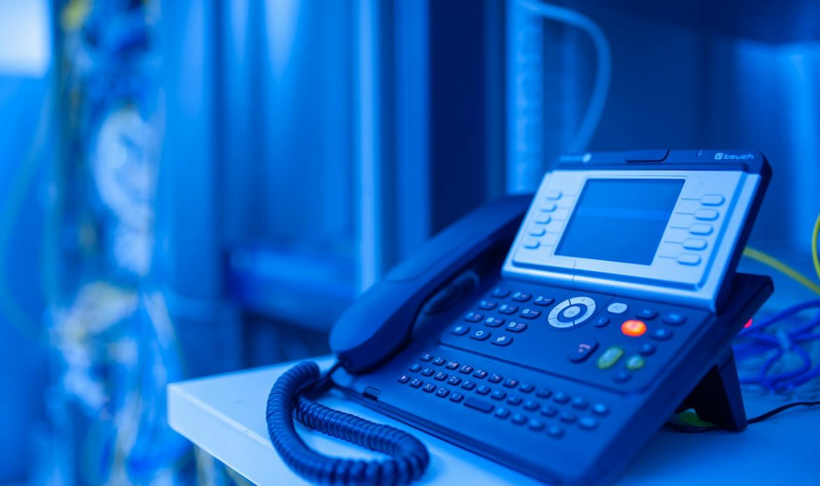 Close-up of a modern office phone in blue lighting. Ideal for tech and business themes.